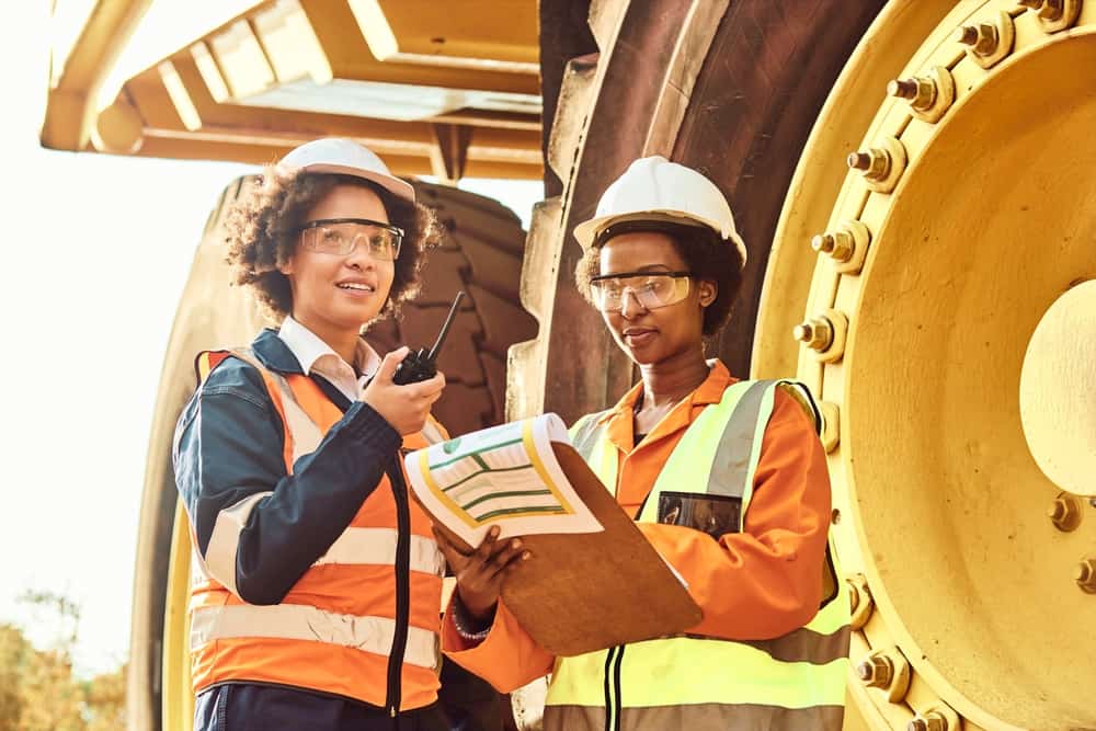 Two female workers near a haul truck.