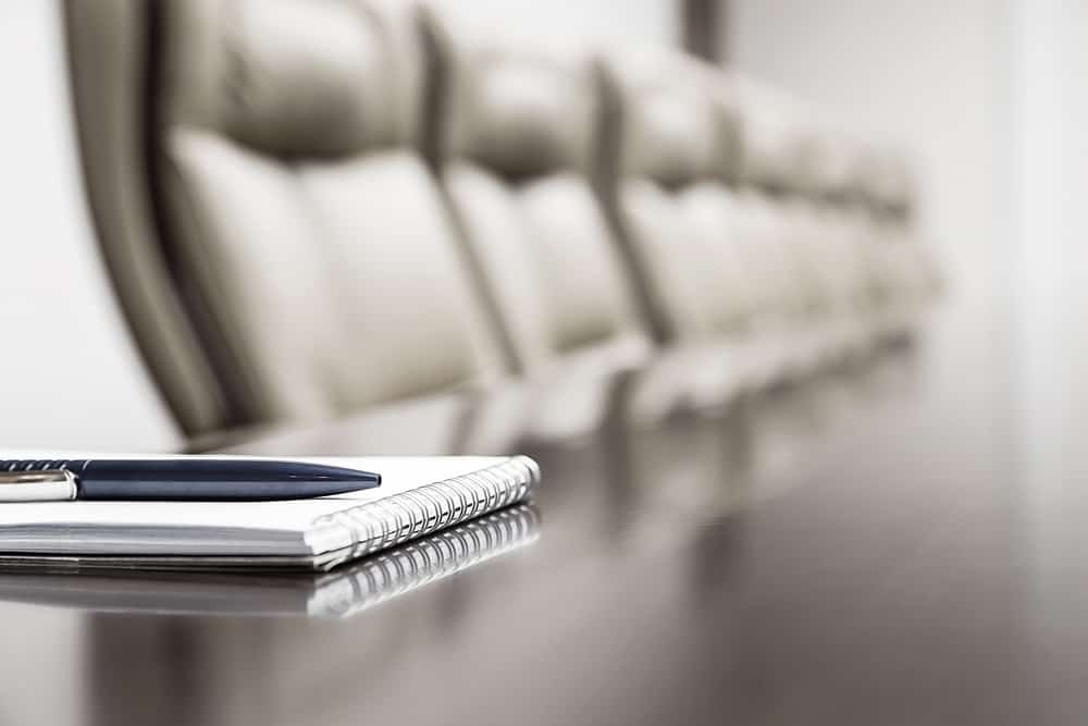 Close up of a pen and pad in a meeting room.